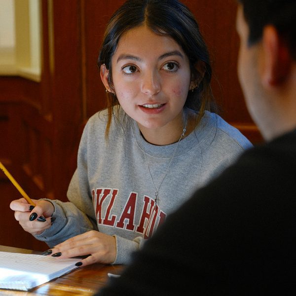 Image of student looking at another student while working on an assignment in the classroom.