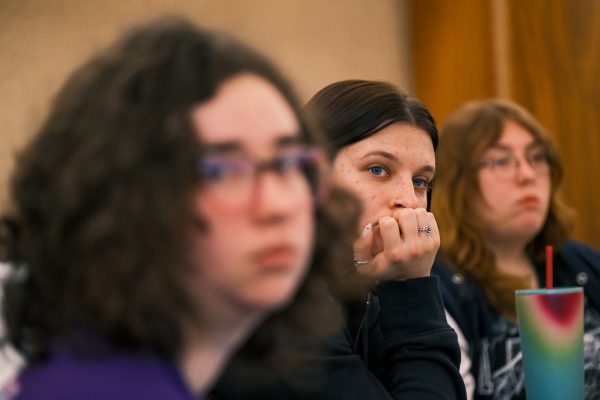 Three students looking at professor during lecture